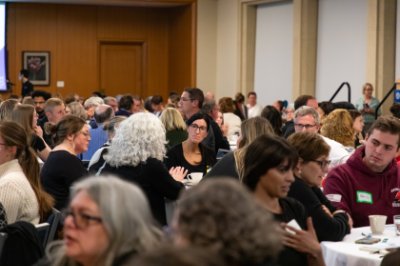 A large group of people seated at round tables engaging in civil discourse